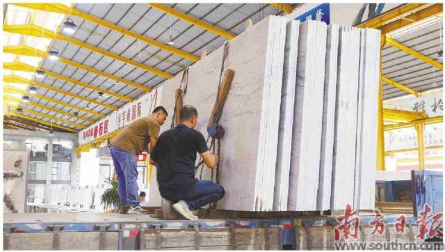    大卖场内，工人正在搬运石材板材。